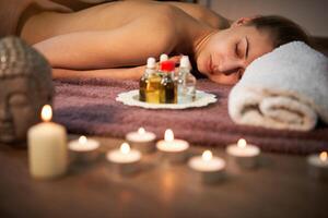 relajarse y disfrutar en spa salón, consiguiendo masaje por profesional masajista. mujer acostado con desnudo espalda relajarse en piso cobija foto