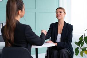 trabajo entrevista. negocio, carrera y colocación concepto. joven rubia mujer apretón de manos candidato mano, mientras sentado en frente de candidato durante corporativo reunión o trabajo entrevista foto