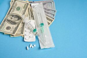 pills empty blisters for drugs individual syringe and money lie on a blue background photo