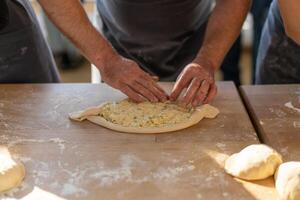 culinario Maestro clase. de cerca de masculino manos preparando khachapuri. tradicional georgiano queso un pan. georgiano comida foto