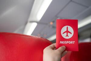 Hand holding passport in the airplane cabin. photo