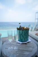 A champagne bottle on bucket filled with ice on with tropical ocean background. photo