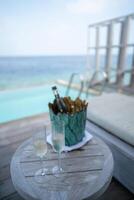 A champagne bottle on bucket filled with ice on with tropical ocean background. photo