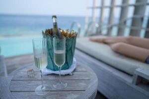 A champagne bottle on bucket filled with ice on with tropical ocean background. photo