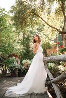 un linda Rizado mujer en un blanco Boda vestir con un Boda ramo de flores y guirnalda en su pelo en pie espalda a el cámara en naturaleza. concepto escapado novia. adelante a un contento brillante futuro huir foto