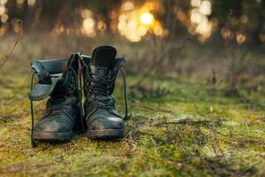 cerca arriba de Clásico par de caminando botas en roca pradera antecedentes. foto