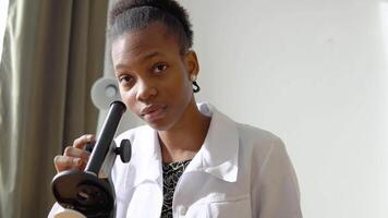 African american female doctor looking through a microscope observing viruses. Female scientist doing some research and looking through a microscope in laboratory video