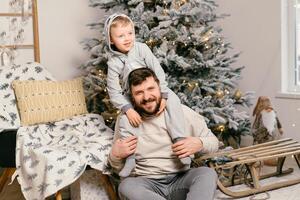 fiesta Navidad hermoso padre jugando con pequeño linda hijo cerca decorado nuevo año árbol a hogar foto