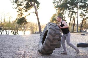 Strong man training workout lifting large tire outdoor DIY gym. photo