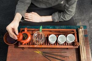 un niña en un gris lino camisa arregla un real ceremonia, clásico accesorios para un té ceremonia. concepto de sano comida y tradicional bebidas foto