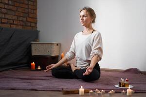 Beautiful young caucasian girl sitting in a room in lotus position meditates photo