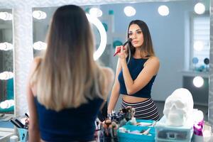 retrato de bonito hembra cosmetólogo en pie posando a lugar de trabajo en pelo y belleza salón foto