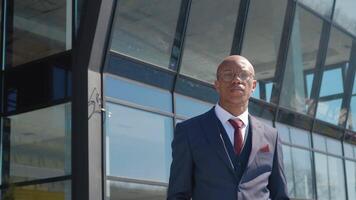 Pensive elegant African American businessman looking at camera close up. Portrait black man in eyeglasses. Black businessman near a modern mirror building video