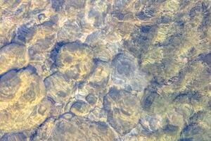 Natural texture in nature with a natural pattern of water waves and stones at the bottom photo