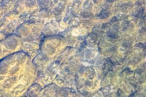 Natural texture in nature with a natural pattern of water waves and stones at the bottom photo