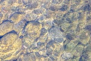 Natural texture in nature with a natural pattern of water waves and stones at the bottom photo