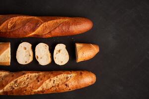 Three crispy french baguettes lie on an old wooden table with free space for text photo