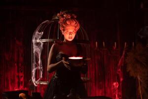 Halloween Witch with cauldron. Beautiful young woman conjuring, making witchcraft photo