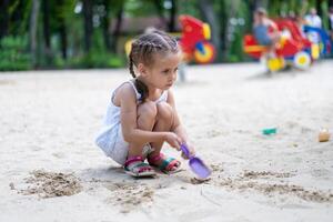 Little Girl Playing Sandbox Playground Digging Sand Shovel Building Sand Figure Summer Day photo