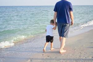 Father son spending time together sea vacation Young dad child little boy walking beach photo