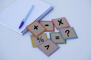 Square paper cards with math symbol signs set, paper notebook and pen. Concept, education material.  Math teaching aid for calculate lesson or playing game. photo