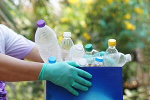 Hand holds used plastic bottle to put in junk bin for recycling. Concept, sorting garbage campaign before throw away for reuse or recycle. Environment conservation. Eco friendly activity. photo