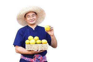 Handsome Asian man farmer wears hat, blue shirt, holds basket of organic orange fruits, show fruit, isolated on white background. Concept, Agriculture occupation, produce crops to market. photo