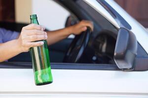 cerca arriba un conductor sostiene botella de cerveza en coche. concepto , Campaña para no lo hagas conducir, no lo hagas bebida alcohol ese lata porque coche accidente y ilegal. peligroso conducción cuando borracho. foto