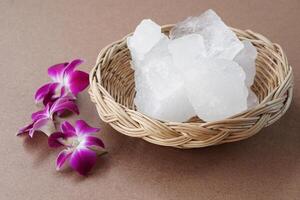 Crystal clear alum stones or Potassium alum on basket, decorated with flowers. Useful for beauty and spa treatment. Use to treat body odor under the armpits as deodorant and make water clear. photo