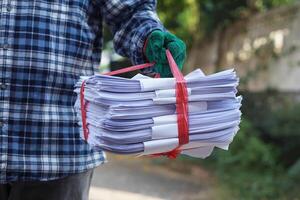 Close up man hold pile of used paper, tied with rope. Concept, sorting garbage for recycle next steps. Eco friendly activity. Waste paper management. Reduce reuse, recycle paper. photo