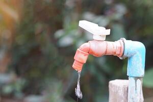 Old water faucet with dripping. Concept. Save water for environment. Turn off tap or faucet  before leaving. Don't waste water by let it dripping or leaking. photo