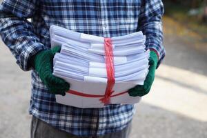 Close up man hold pile of used paper, tied with rope. Concept, sorting garbage for recycle next steps. Eco friendly activity. Waste paper management. Reduce reuse, recycle paper. photo