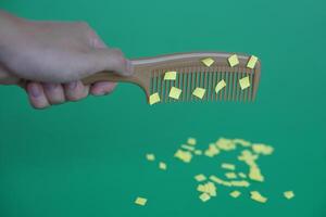 Comb and small pieces of paper. Equipment, prepared to do experiment about static electricity. Green background. Concept, Science lesson, fun and easy experiment. Education. Teaching aids. photo