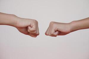 Close up  two hands bump their fists together for greeting. Concept, Body language. Hands gesture symbol for greeting, giving respect or approval as companionship between two people. photo