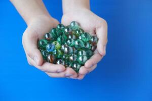 Close up hands holds marbles balls, small spherical object often made from glass, clay, steel, plastic, or agate. Concept. object use as toy for playing games or use for DIY craft decoration. photo