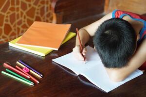 Unidentified boy faced down on table, feel lazy to do homework at home. Concept , Students don't want to study. Lose concentration. photo