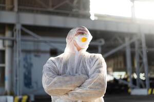 COVID-19 coronavirus doctor standing hospital parking dressed white protective overalls hazmat suit. photo