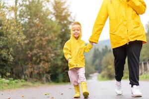 Rainy day Mother and little daughter walking after rain dressed yellow raincoat photo