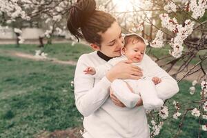 young mother with adorable daughter in park with blossom tree. Happy mother and child photo