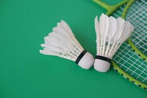 Shuttlecock and rackets. Badminton sport equipments on green background. Concept, sport, exercise, recreation activity for good health. Popular sport for all genders photo