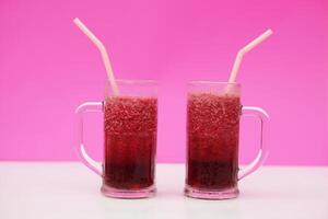 Glass of red fruit smoothie with drinking straw, pink background. Concept, healthy beverage for health. Well being and weight loss menu. Homemade refreshing drinks. High fibers, detox. photo