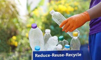 Hand holds used plastic bottle to put in junk bin for recycling. Concept, sorting garbage campaign before throw away for reuse or recycle. Environment conservation. Eco friendly activity. photo