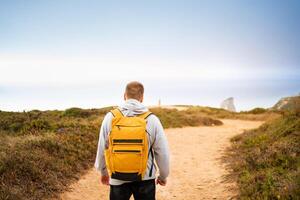 Back view young man traveler with yellow backpack photo