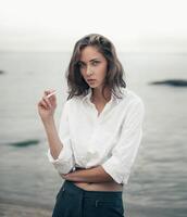 Cute woman smokes a cigarette on the beach photo