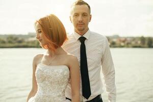 Elegant gentle stylish groom and bride near river or lake. Wedding couple in love photo