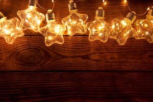 brillante luminoso Navidad guirnaldas en el forma de estrellas mentira en un oscuro de madera antecedentes. foto