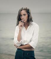 Cute woman smokes a cigarette on the beach photo