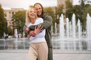 Couple in love walking outdoors park fountain Caucasian man woman walk outside after jogging dressed sport clothes photo