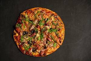 Appetizing pizza with smoked sausages bacon meat tomato cheese arugula photo