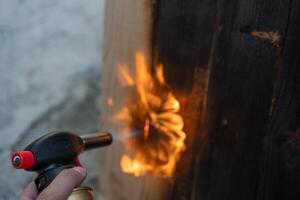 profesional carpintero utilizando antiguo tradicional japonés técnica. ardiente madera tablones con gas quemador foto